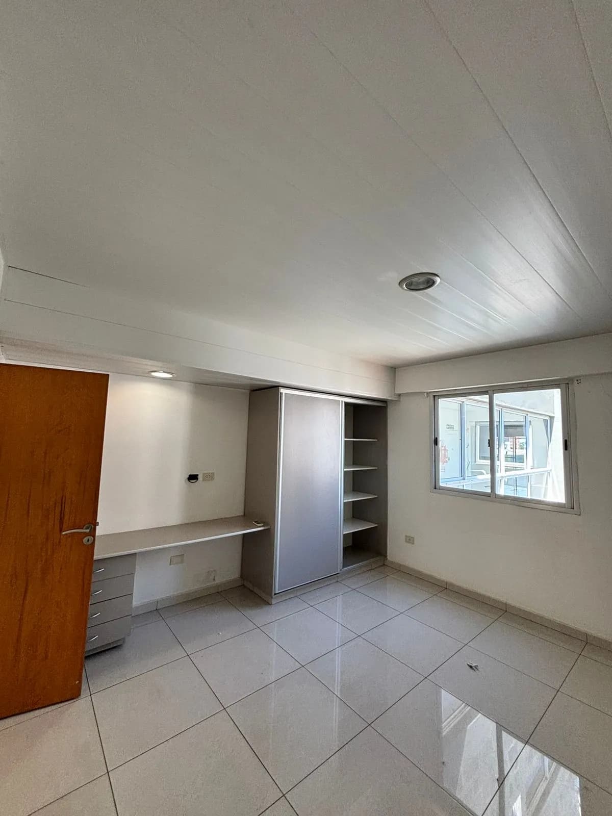 Habitación luminosa con escritorio y placard