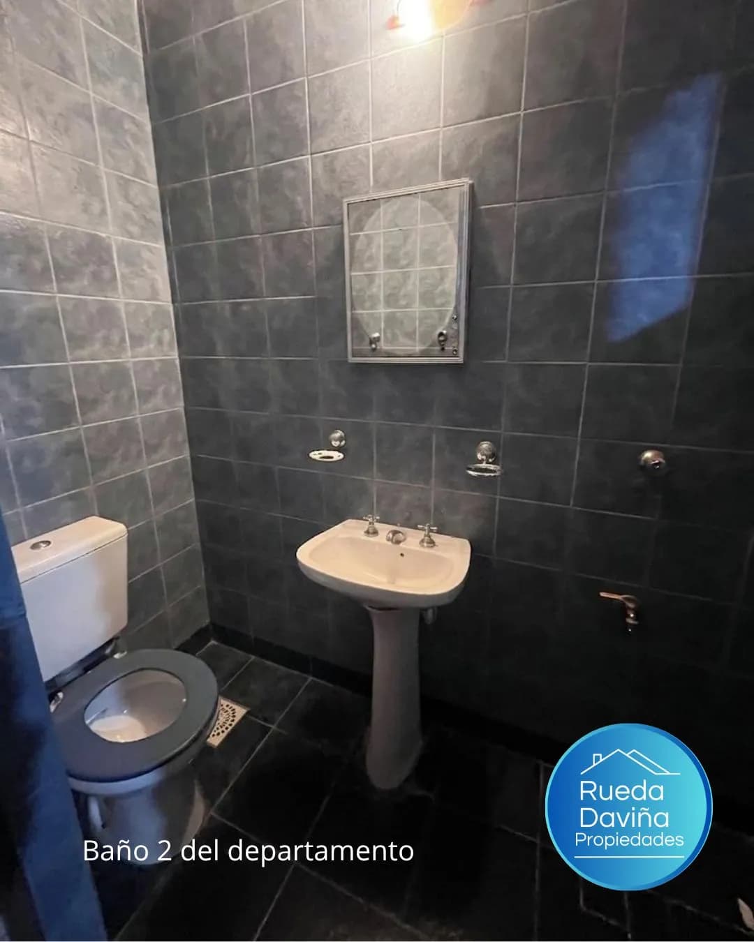 Baño secundario con azulejos oscuros